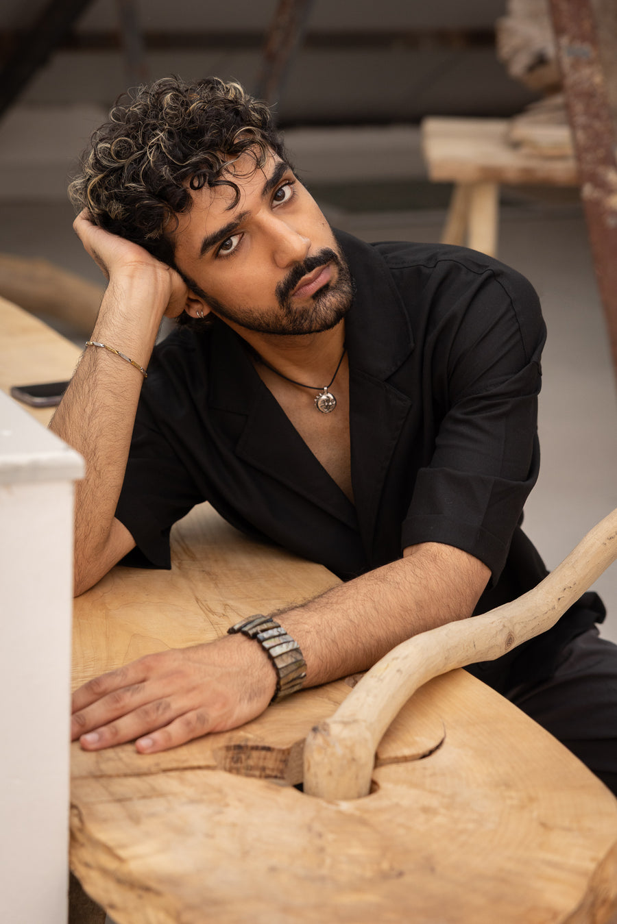 Man in black shirt leaning on wooden surface with rustic background