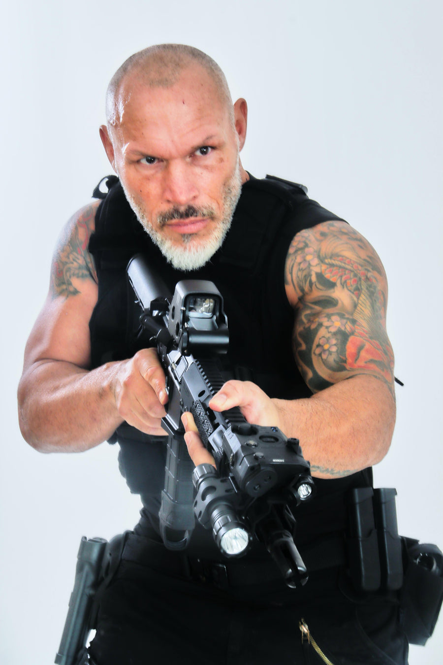 Man with tattoos holding a rifle against a white background taken at our Sonder SPACT Character Profile Session.