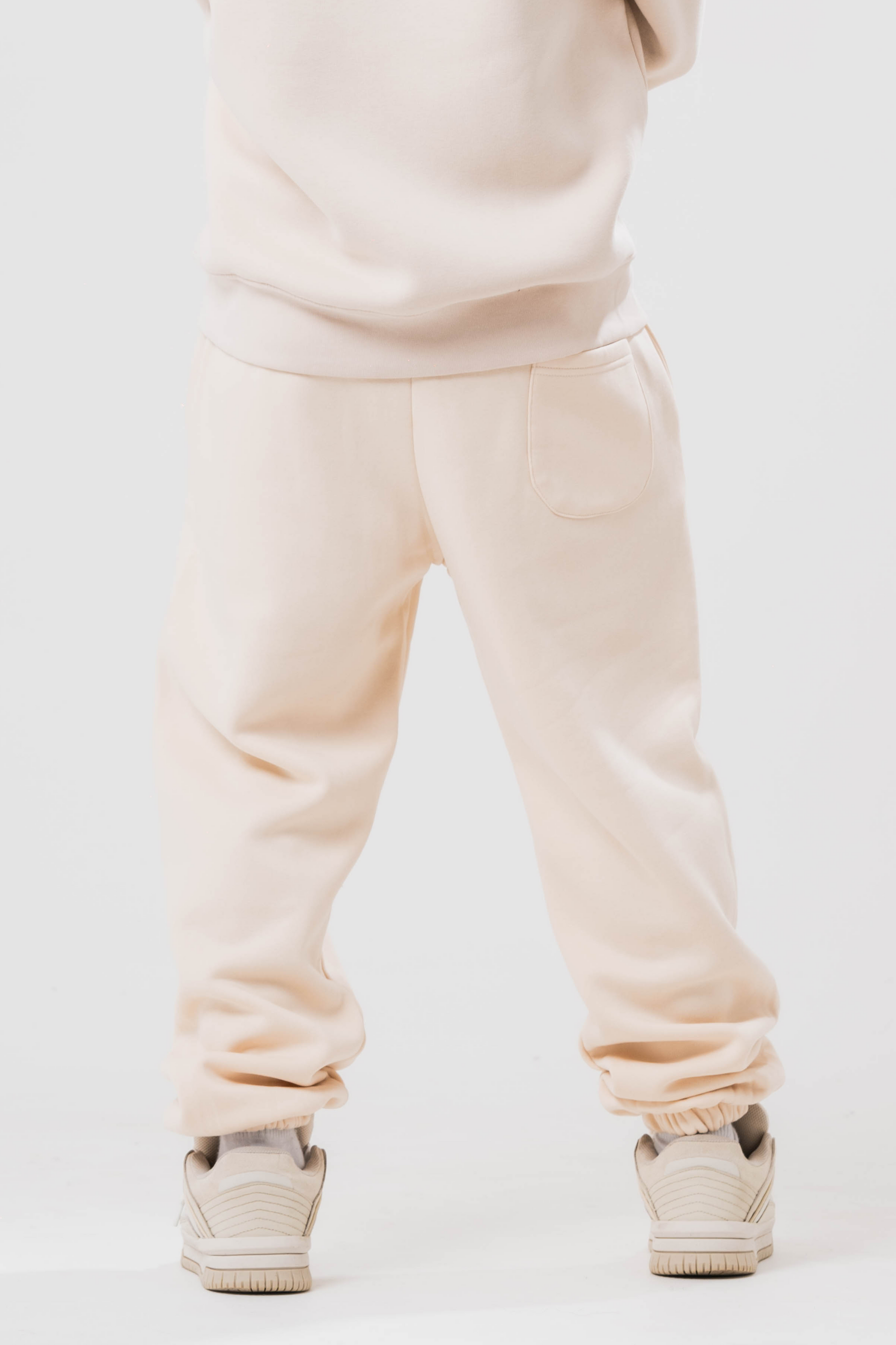 Back view of Male model wearing the Sonder Beige Oversized zip hoodie with the oversized joggers. Standing in front of a light grey background.