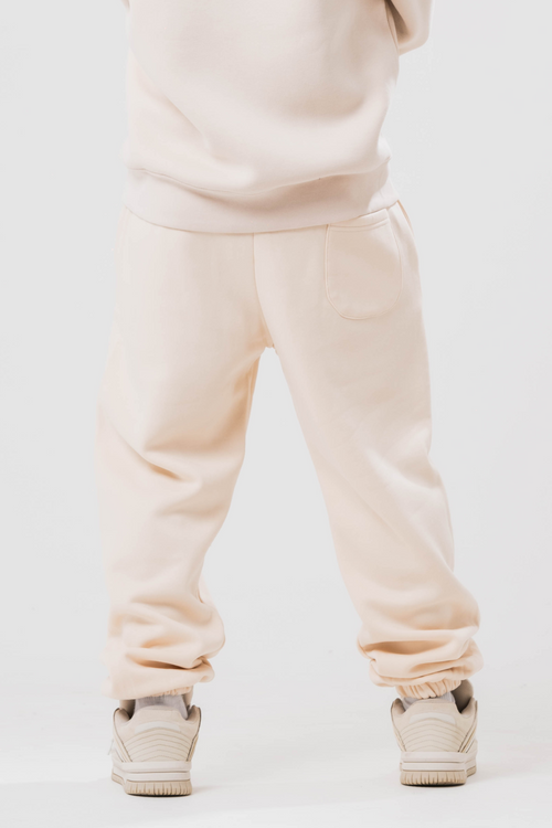 Back view of Male model wearing the Sonder Beige Oversized zip hoodie with the oversized joggers. Standing in front of a light grey background.