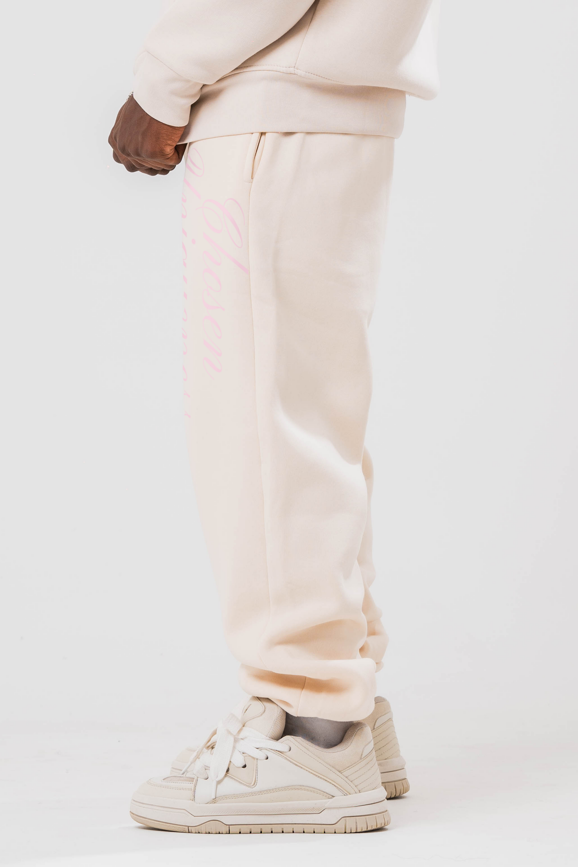 Side view of Male model wearing the Sonder Beige Oversized zip hoodie with the oversized joggers. Standing in front of a light grey background.