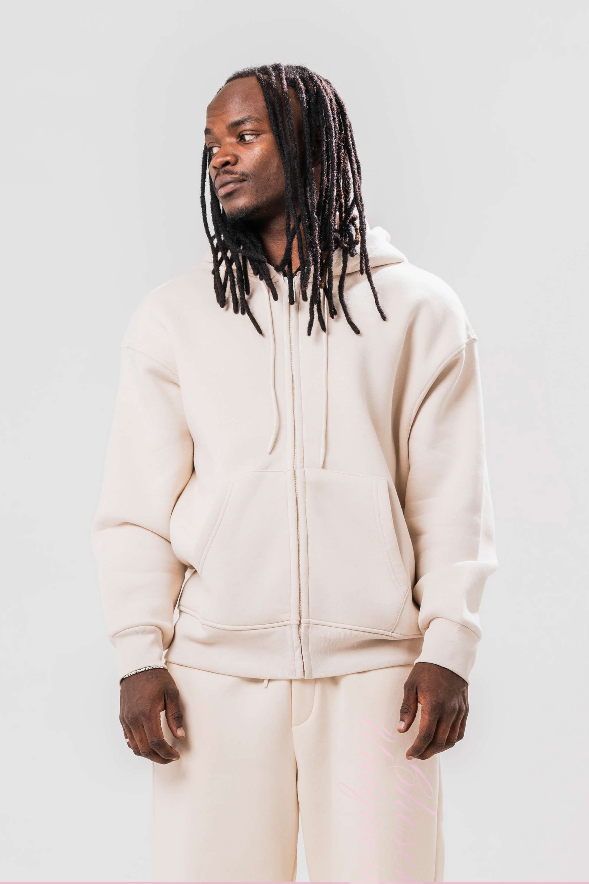 Male model wearing the Sonder Beige Oversized zip hoodie with the oversized joggers. Standing in front of a light grey background.