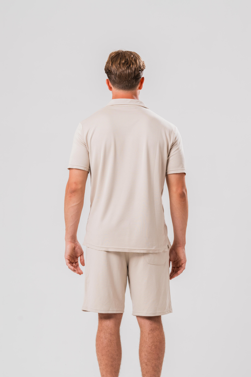Back view of Male model wearing the Sonder Beige Summer Set including the Polo Shirt and shorts, in front of a light grey background