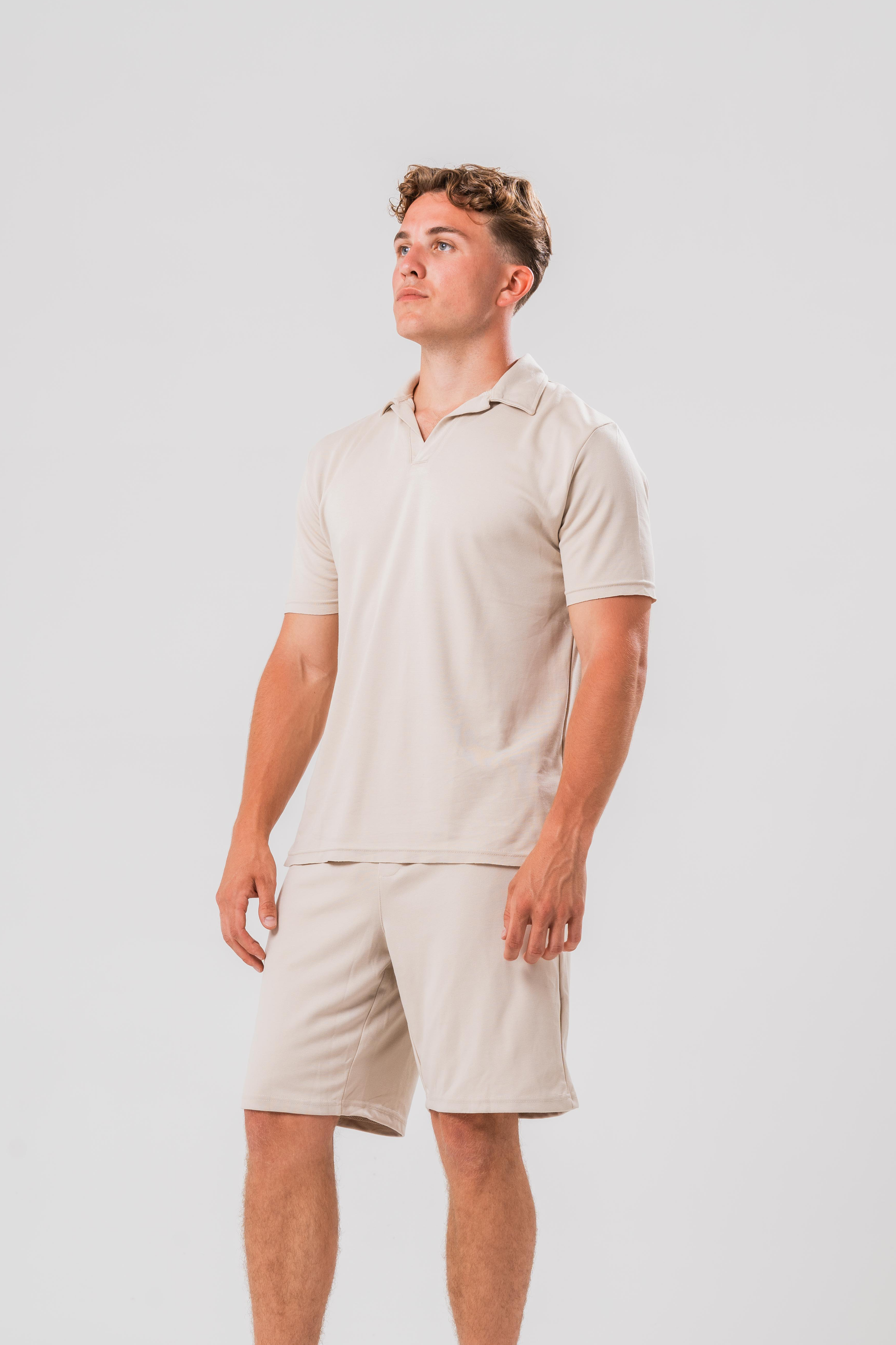 Side View of Male model wearing the Sonder Beige Summer Set including the Polo Shirt and shorts, in front of a light grey background