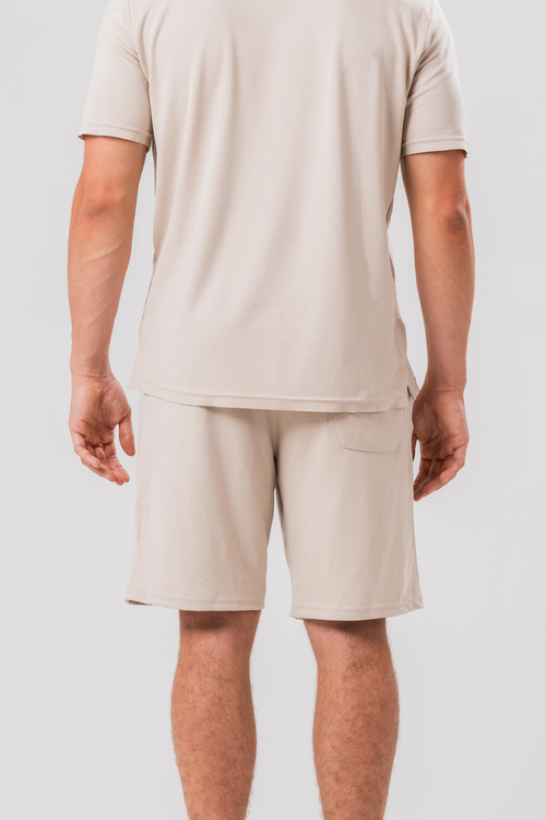 Back view of Male model wearing the Sonder Beige Summer Set including the Polo Shirt and shorts, in front of a light grey background