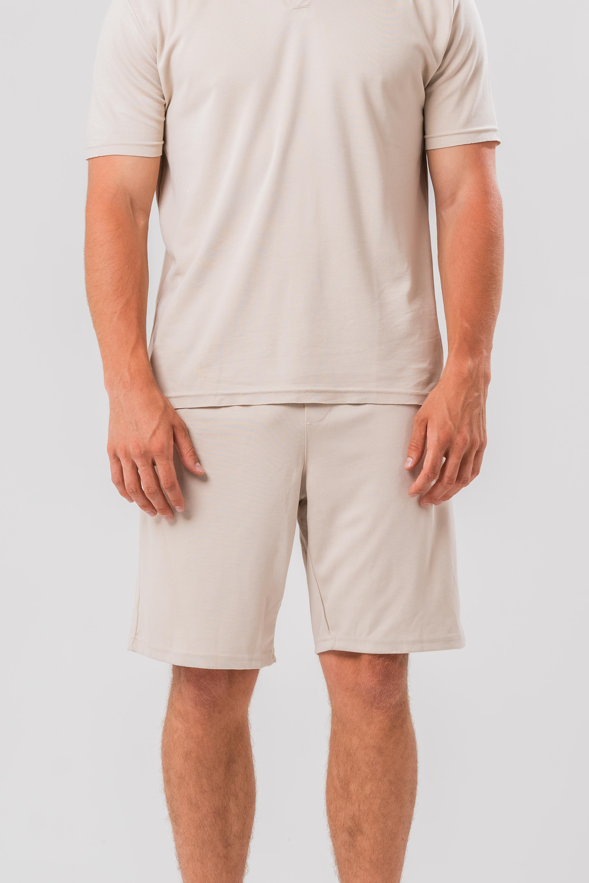 Close up view of Male model wearing the Sonder Beige Summer Set including the Polo Shirt and shorts, in front of a light grey background