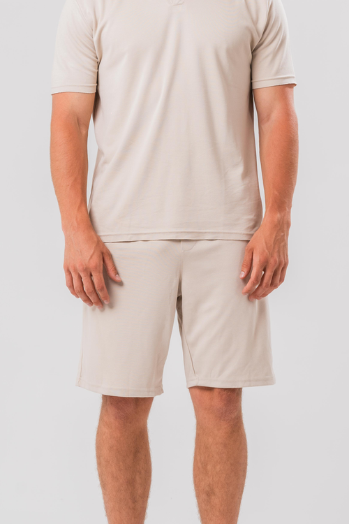 Close up view of Male model wearing the Sonder Beige Summer Set including the Polo Shirt and shorts, in front of a light grey background
