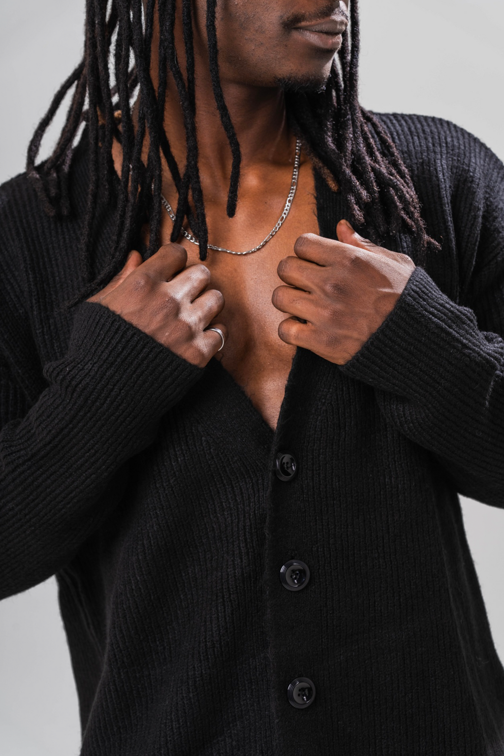 Close up of Male model wearing the Sonder Black Knit Cardigan. In front of a light grey background.