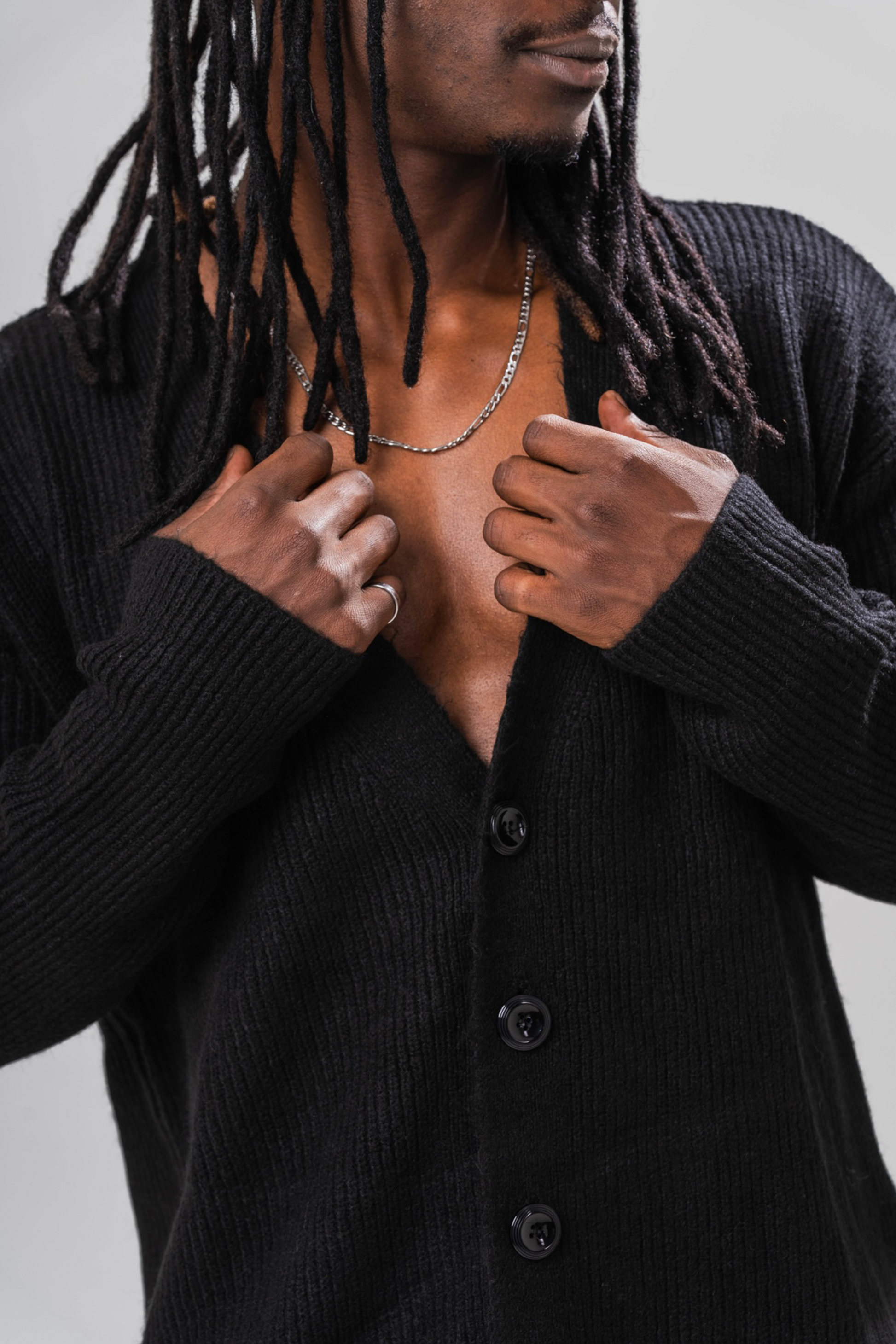 Close up of Male model wearing the Sonder Black Knit Cardigan. In front of a light grey background.