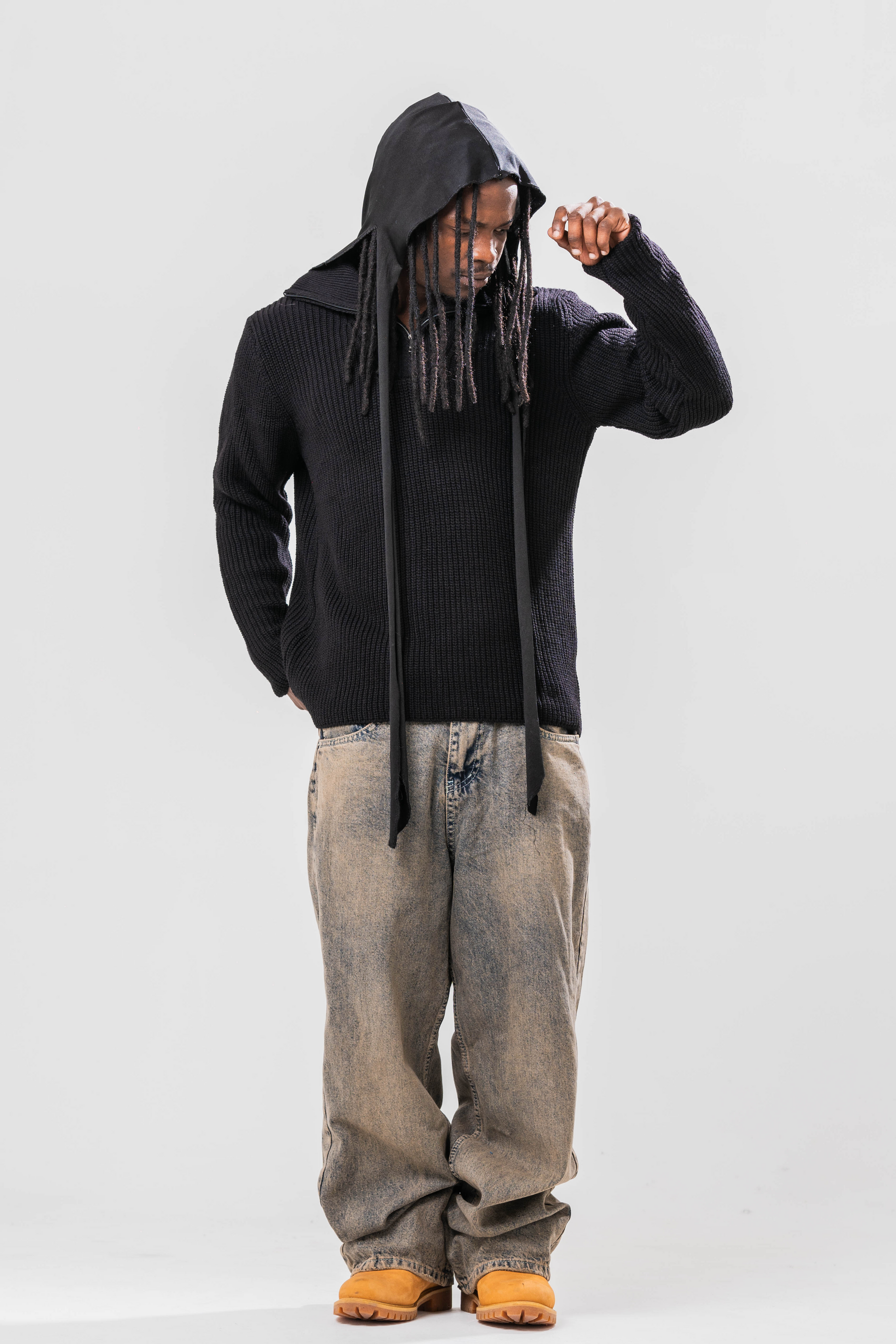 Male model wearing the Sonder Black Knit Quarter Zip with baggy jeans and a durag. In Front of a light grey background.