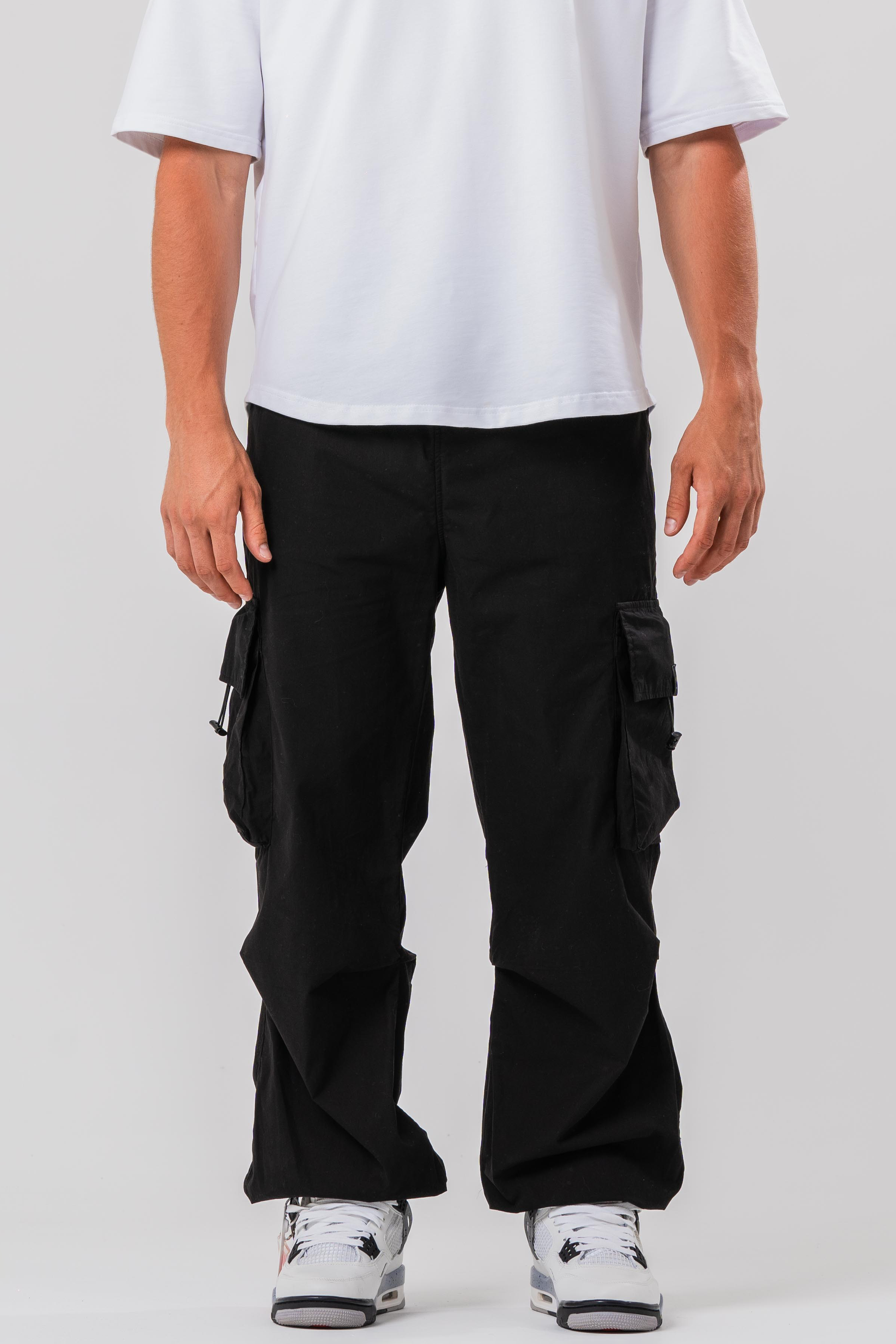 Male model wearing the Sonder Black Oversized Cargo Pants and Sonder White Oversized Graphic Cowboy T-Shirt. In front of light grey background.