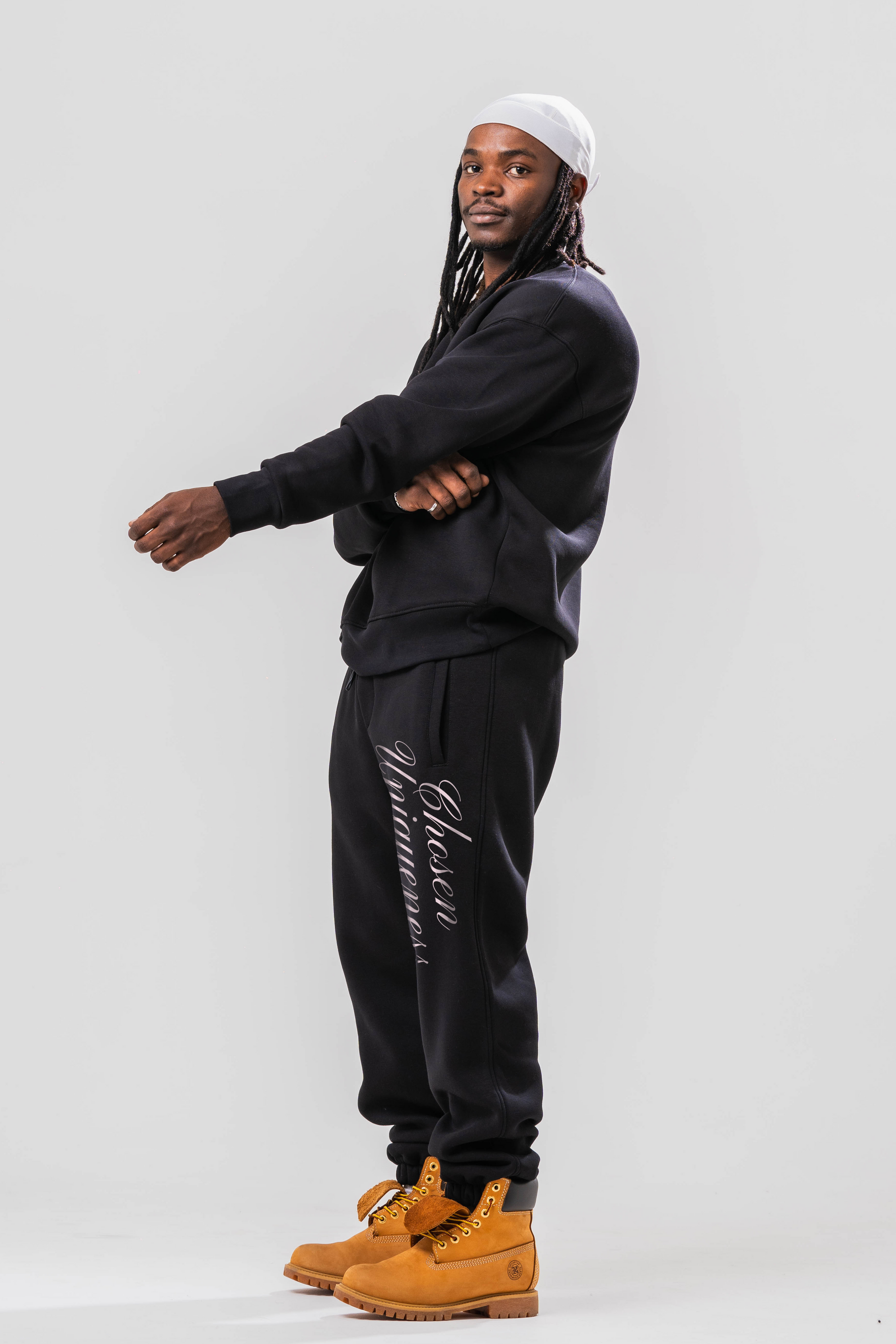 Side view of Male model wearing the Sonder Black Oversized sweatshirt with the oversized joggers. Standing in front of a light grey background.
