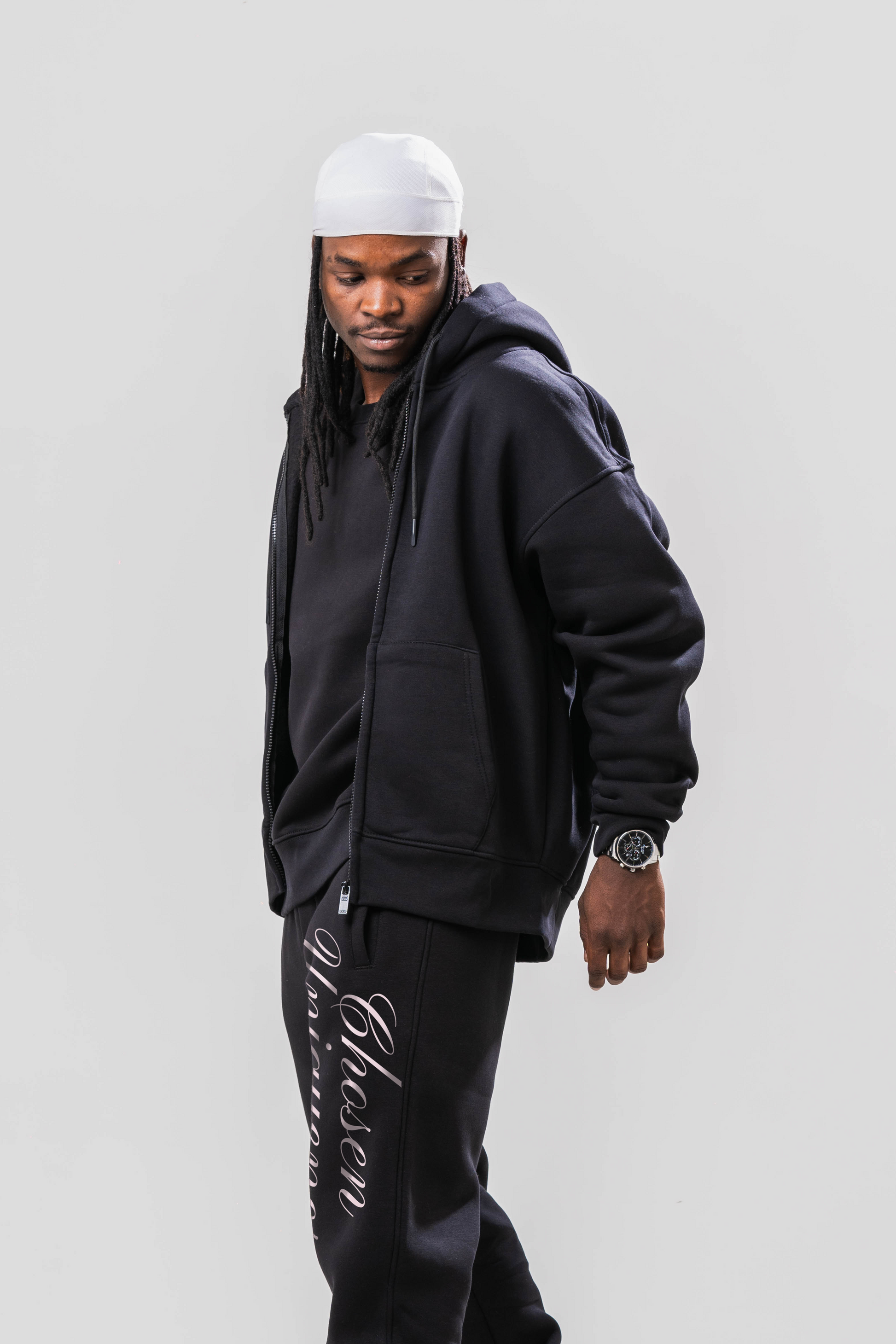 Male model wearing the Sonder Black Oversized zip hoodie with the oversized joggers and black tee. Standing in front of a light grey background.