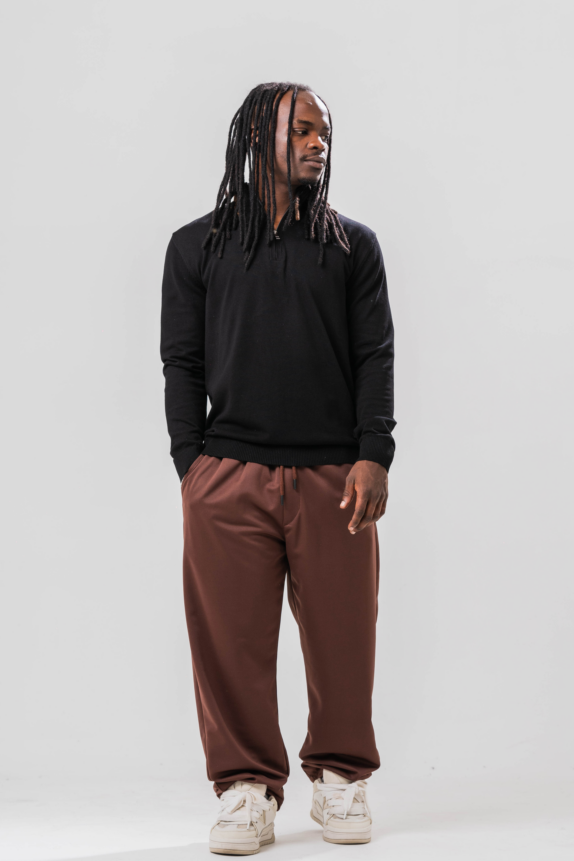 Male model wearing the Sonder Black Quarter Zip paired with our relaxed brown joggers