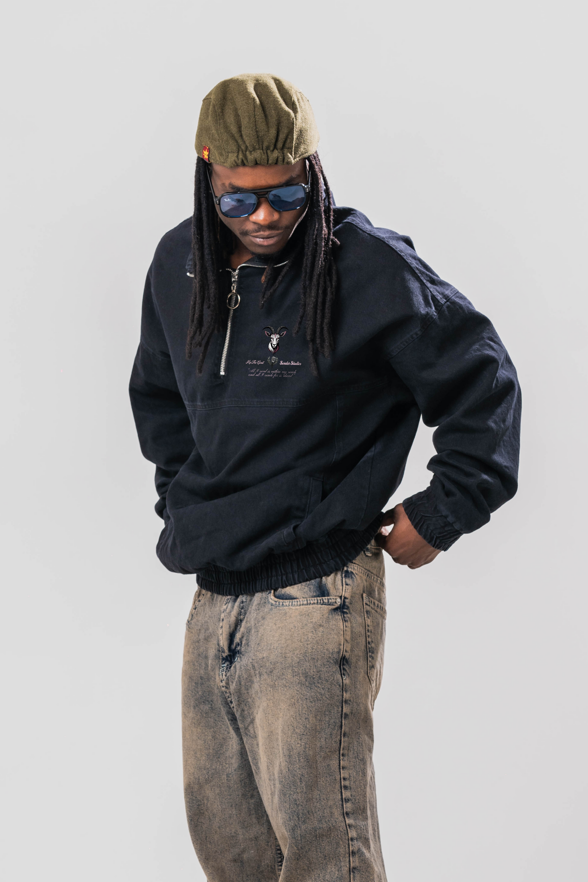 Male model wearing the Sonder Black Quarter zip pullover part of our AP collection, with jeans and a hat in front of light grey background.