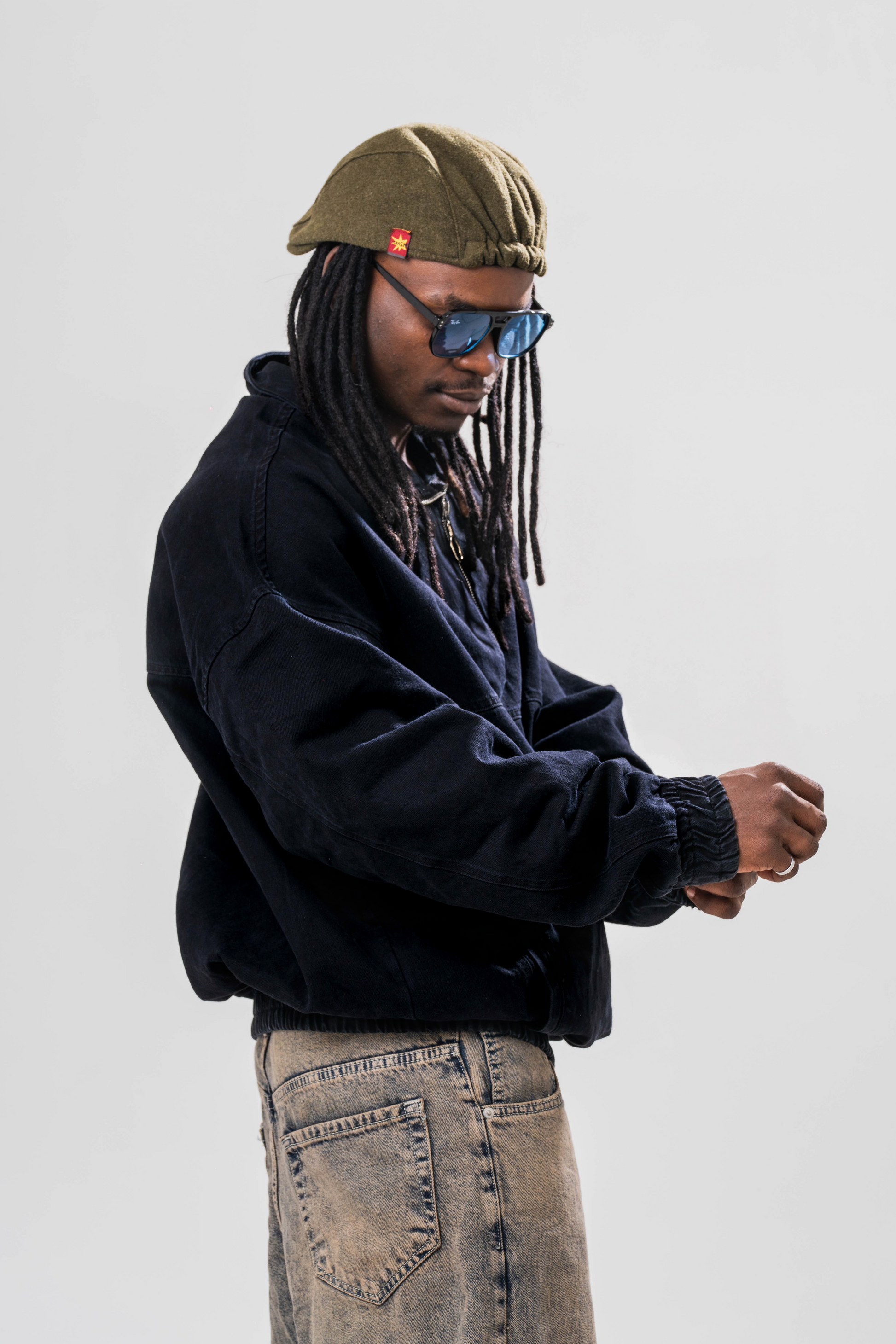 Side view of Male model wearing the Sonder Black Quarter zip pullover part of our AP collection, with jeans and a hat in front of light grey background.
