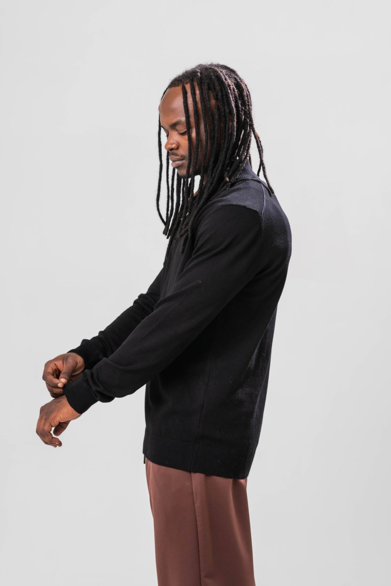 Side view of Male model wearing the Sonder Black Quarter Zip paired with our relaxed brown joggers