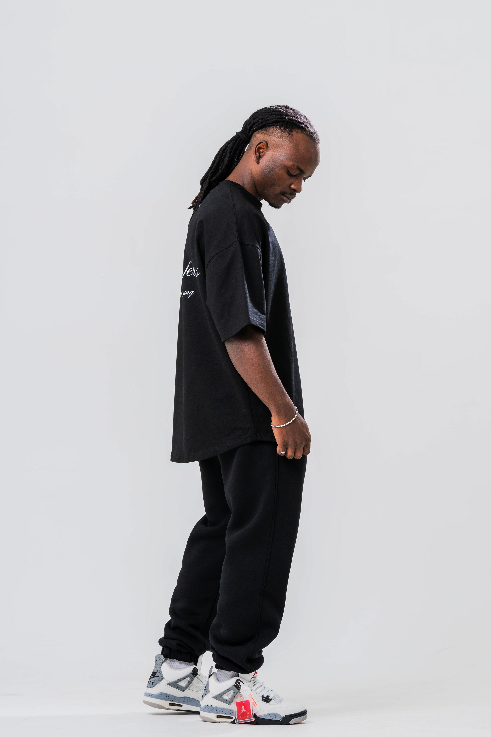 Side view of Male model wearing the Sonder Signature Series Black oversized t-shirt and black joggers, in front of a light grey background