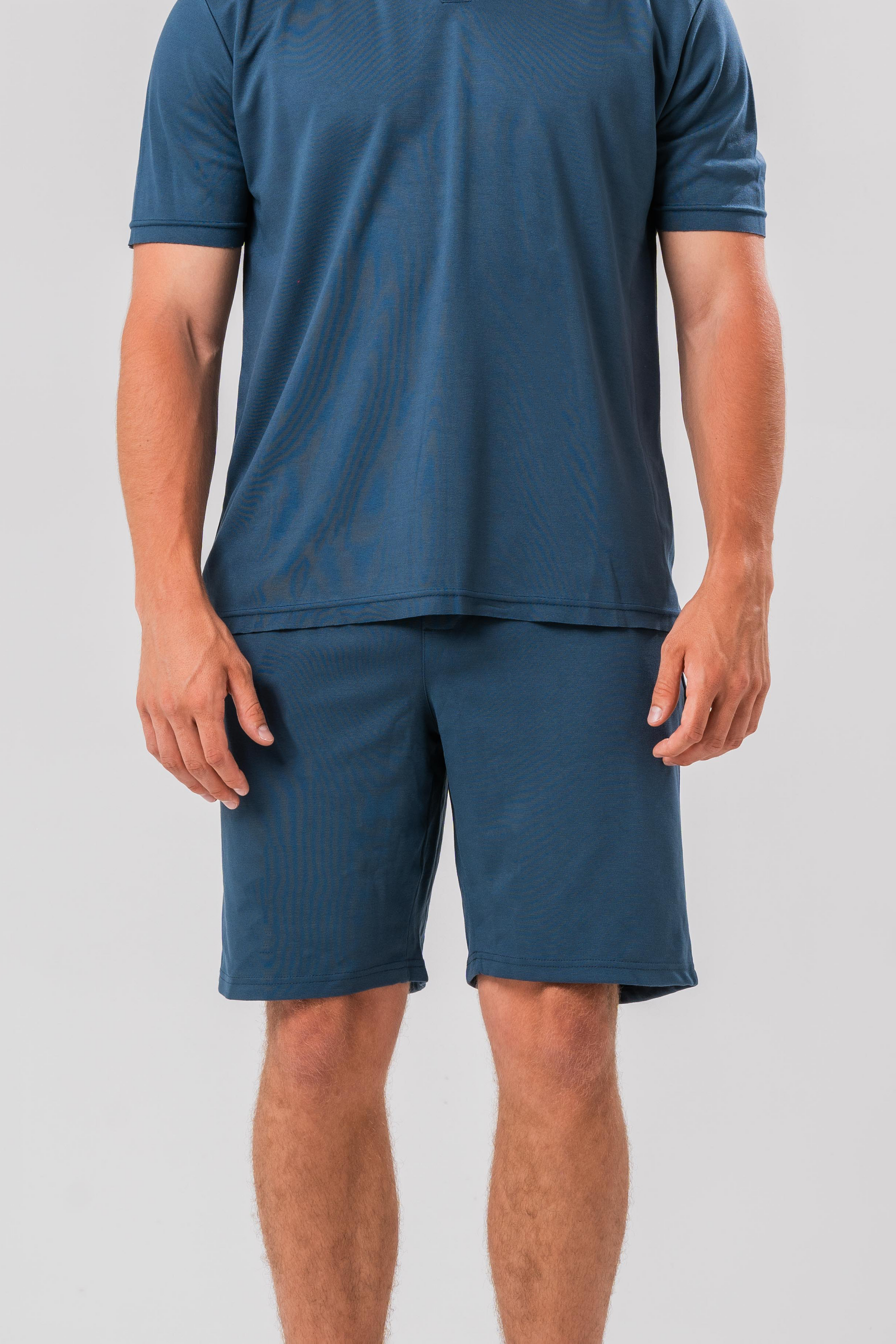 Male model wearing the Sonder Blue Cotton Set including the Polo Shirt and shorts, in front of a light grey background