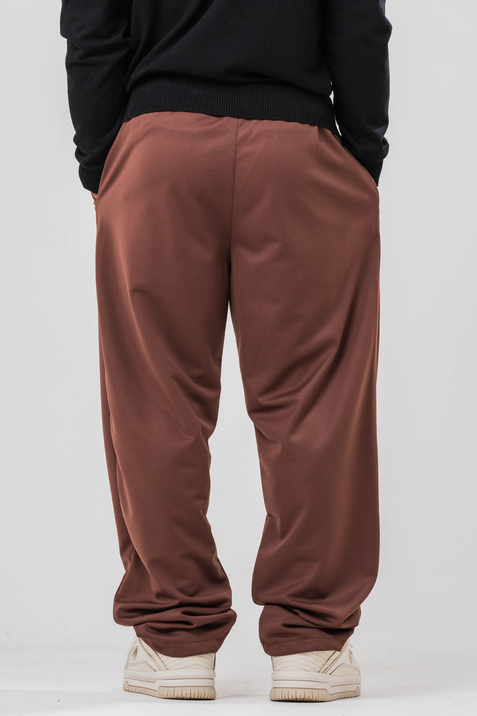 Back view of Male model wearing the Sonder Brown Relaxed Sweatpants and the black quarter zip. Standing in front of a light grey background.