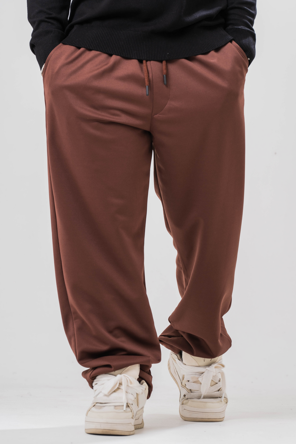 Male model wearing the Sonder Brown Relaxed Sweatpants and the black quarter zip. Standing in front of a light grey background.