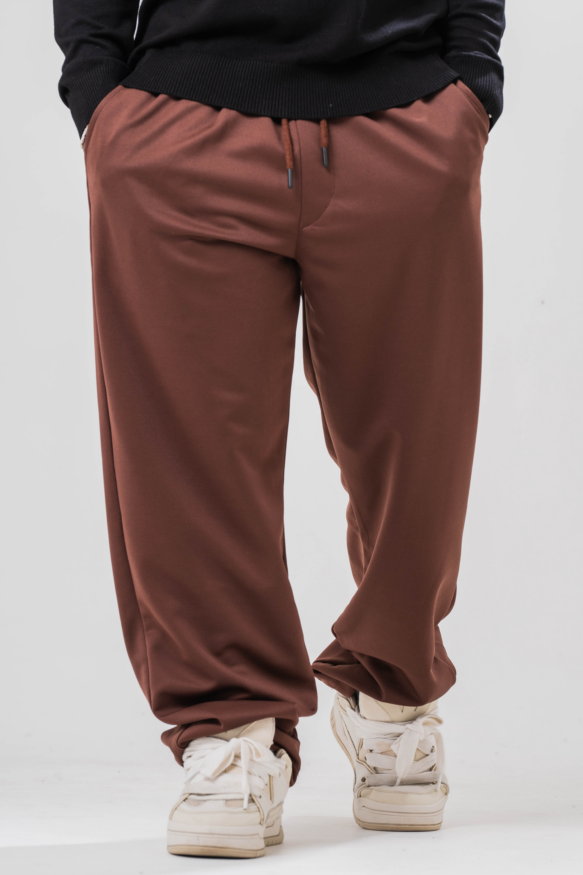 Male model wearing the Sonder Brown Relaxed Sweatpants and the black quarter zip. Standing in front of a light grey background.