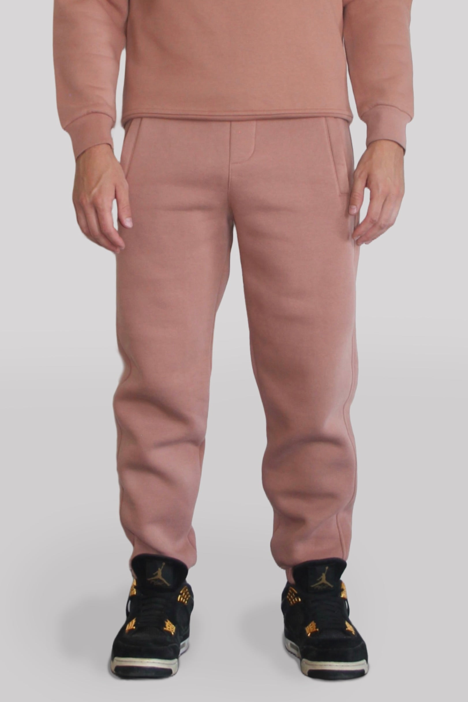 Male model wearing the Sonder Copper Signature Series Sweatpants paired with the Copper Signature Series Sweatshirt. In front of a light grey background