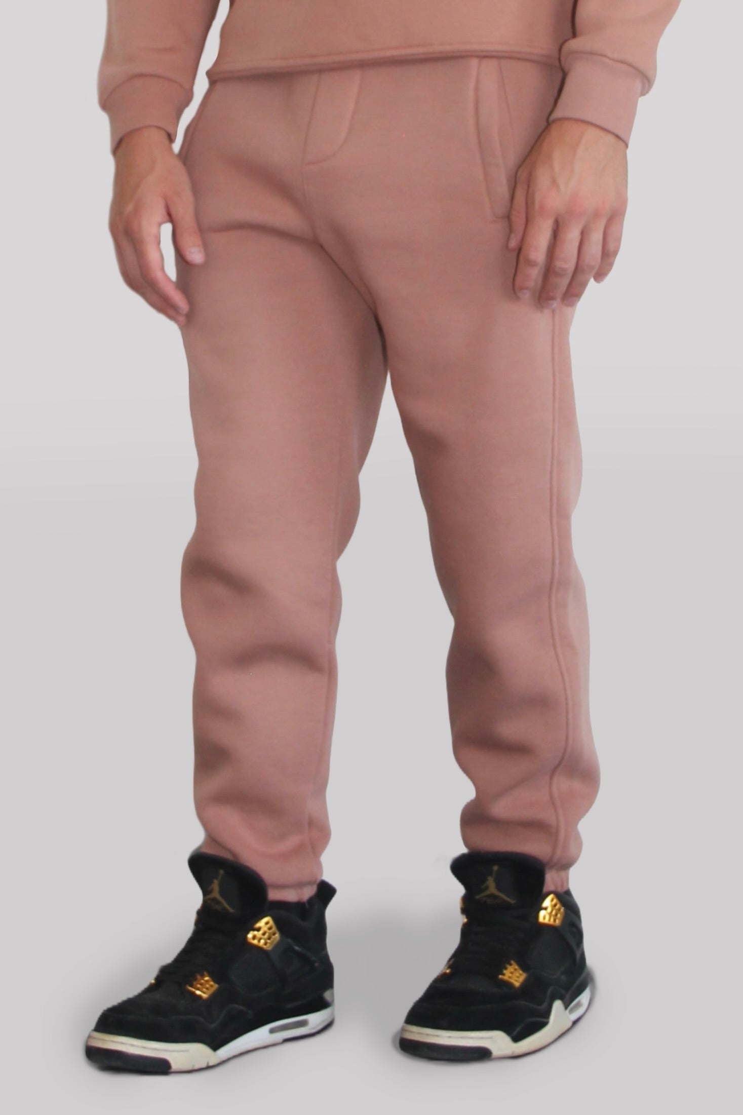 Side view of Male model wearing the Sonder Copper Signature Series Sweatpants paired with the Copper Signature Series Sweatshirt. In front of a light grey background