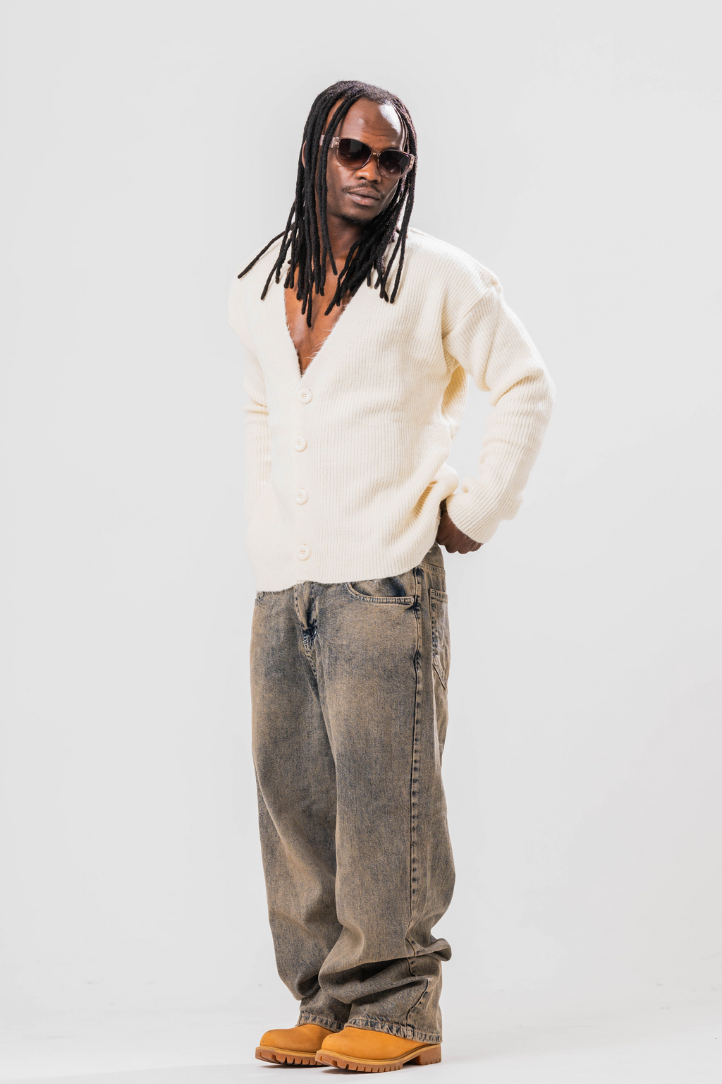 Male model wearing Sonder cream knit cardigan and baggy jeans. On a light grey background