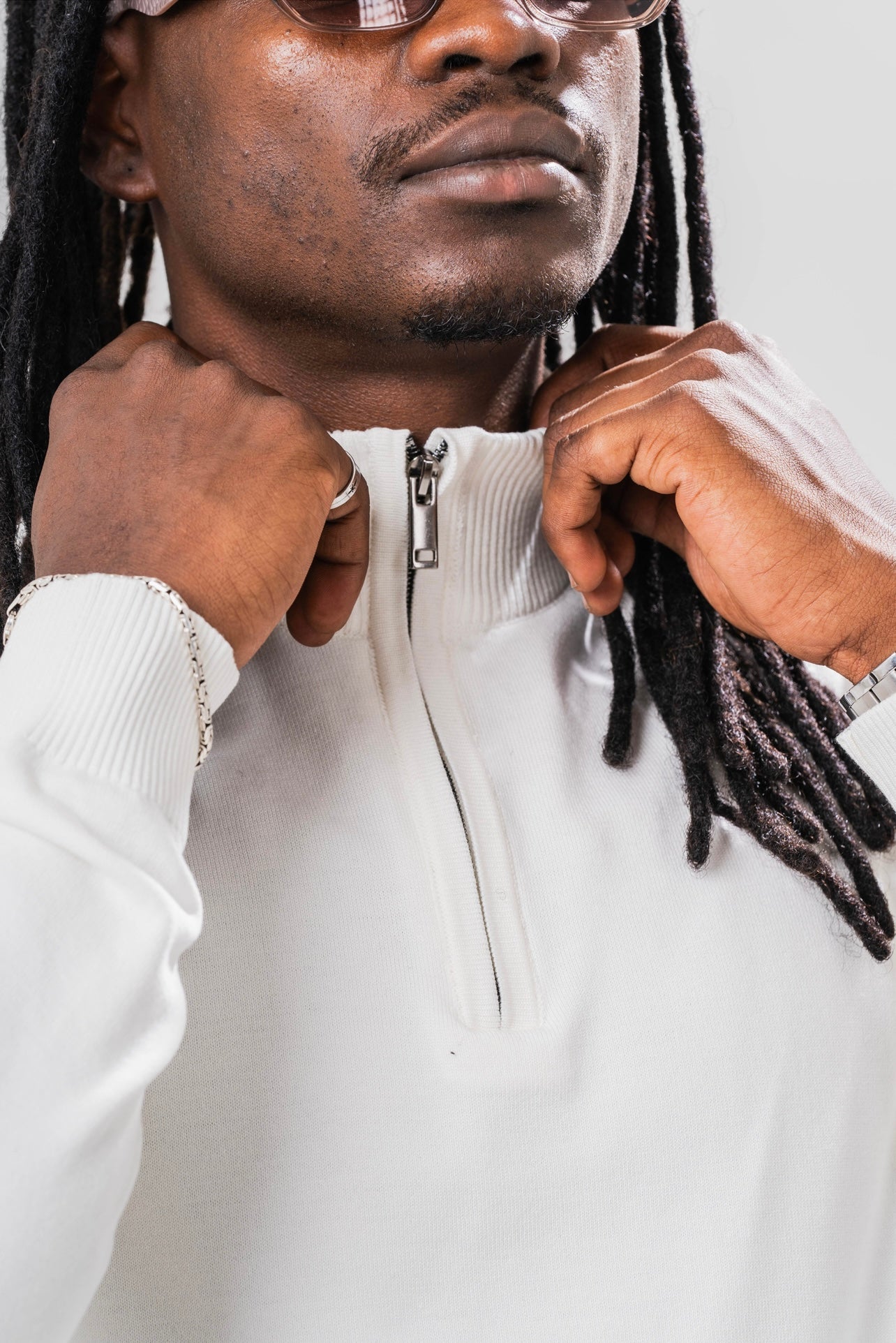 Close up view of male model wearing the Sonder Cream Quarter Zip and holding the collar.