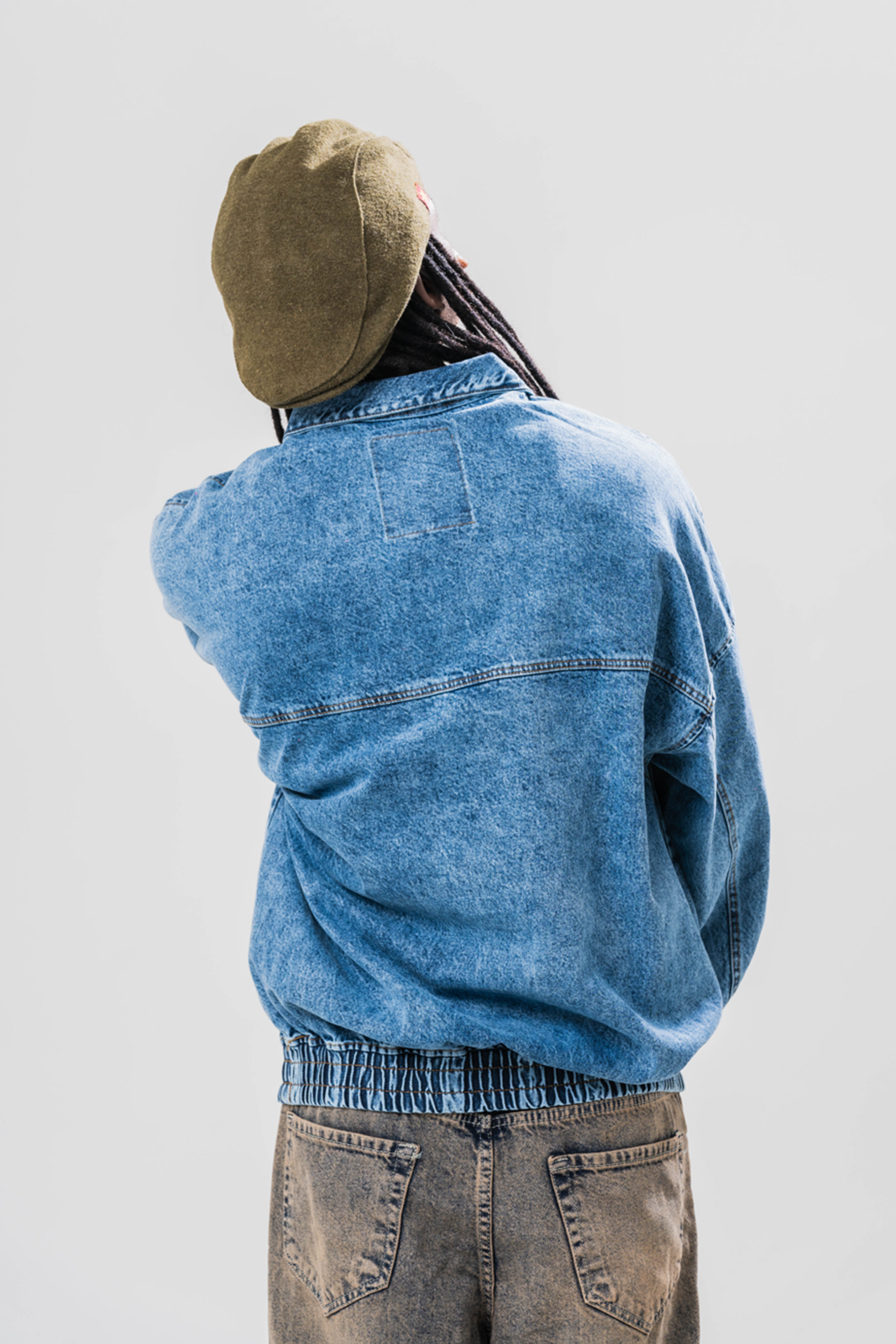 Back view of Male model wearing our Denim Quarter Zip Pullover, also wearing a hat and baggy jeans