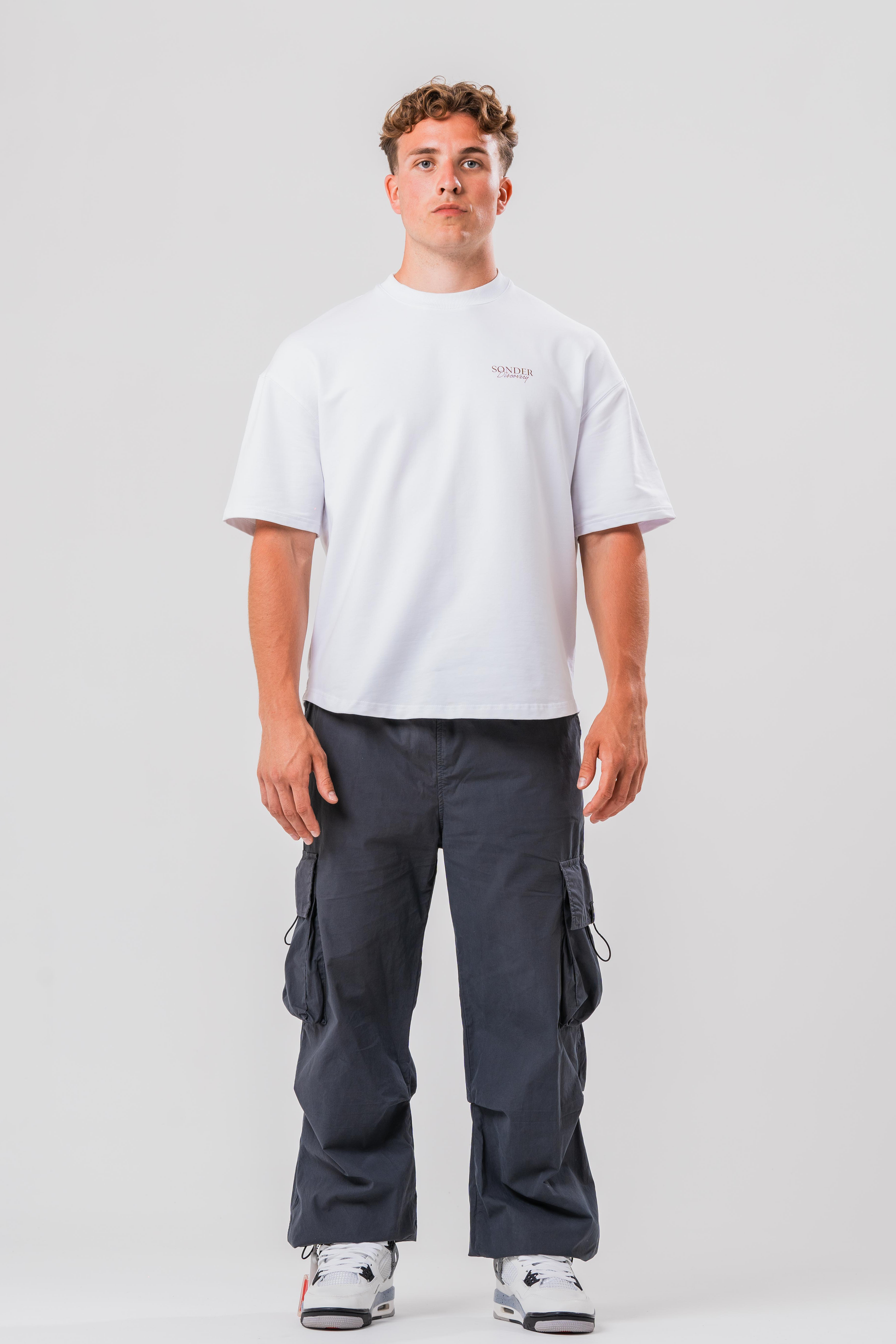 Full fit of Male model wearing the Sonder Grey Oversized Cargo Pants and Sonder White Oversized Graphic Cowboy T-Shirt. In front of light grey background.