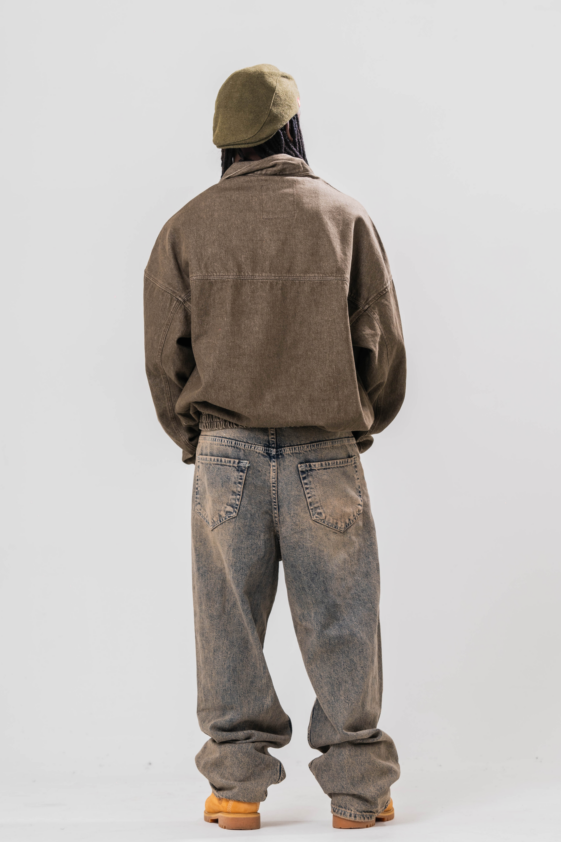 Back view Male model wearing our Khaki Denim Quarter Zip Pullover, also wearing a hat and baggy jeans