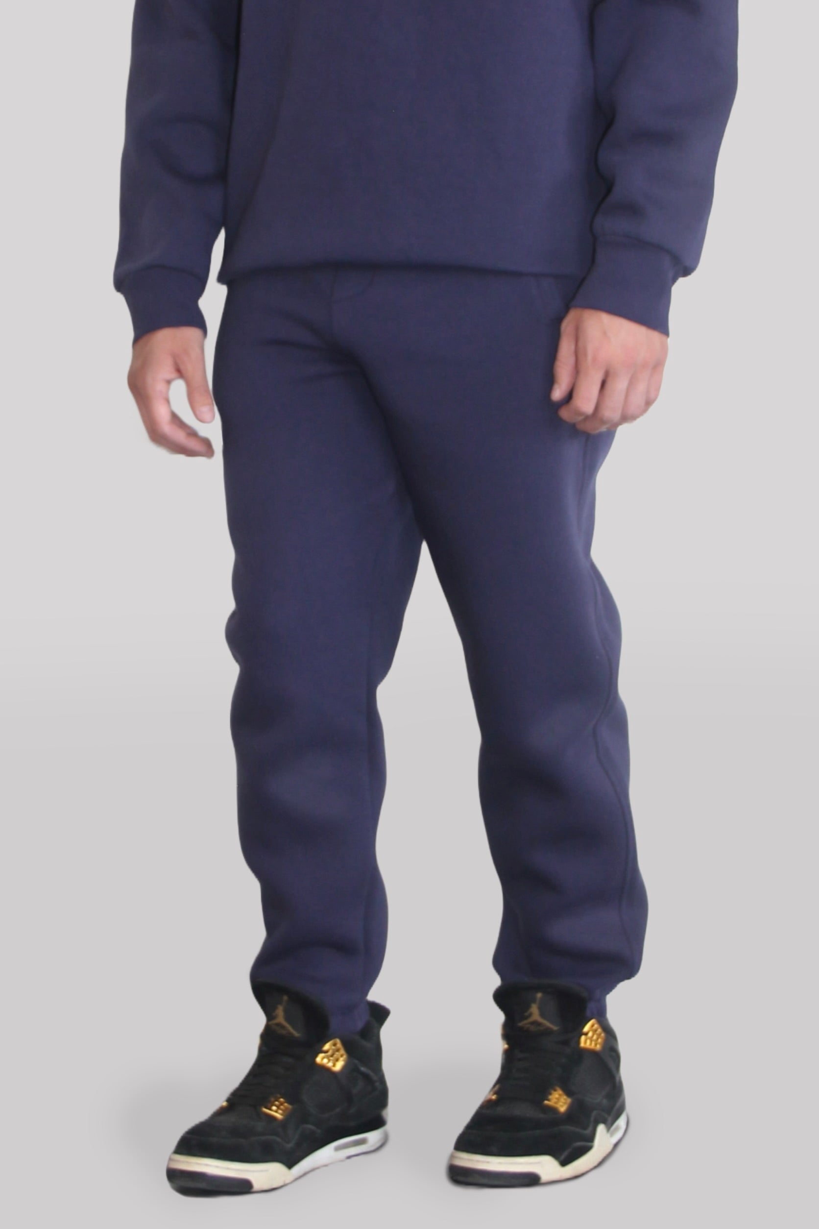 Side view of Male model wearing the Sonder Navy Signature Series Sweatpants paired with the Navy Signature Series Sweatshirt. In front of a light grey background