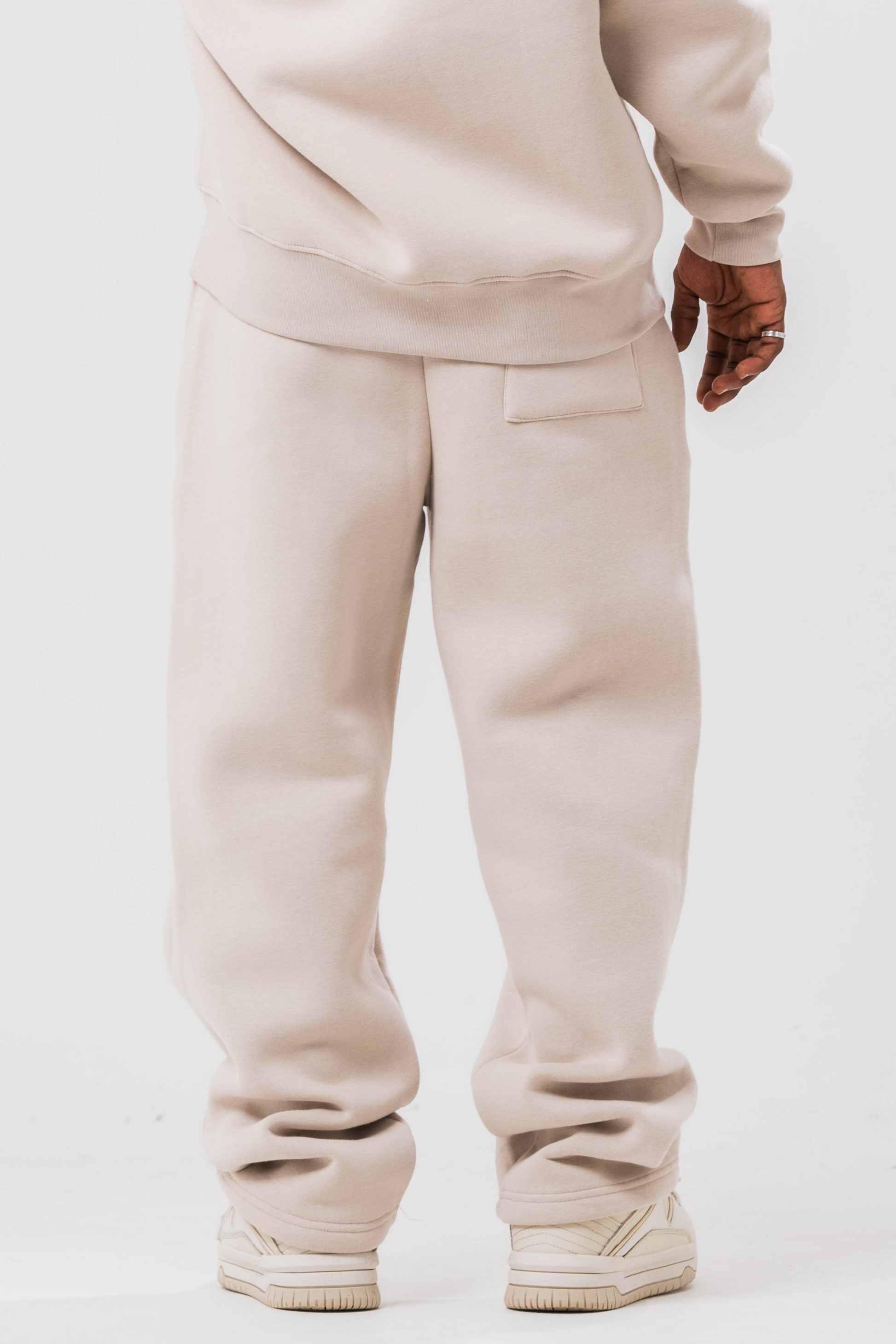Back view of Male model wearing the Sonder Off-White Oversized sweatshirt with the oversized joggers. Standing in front of a light grey background.