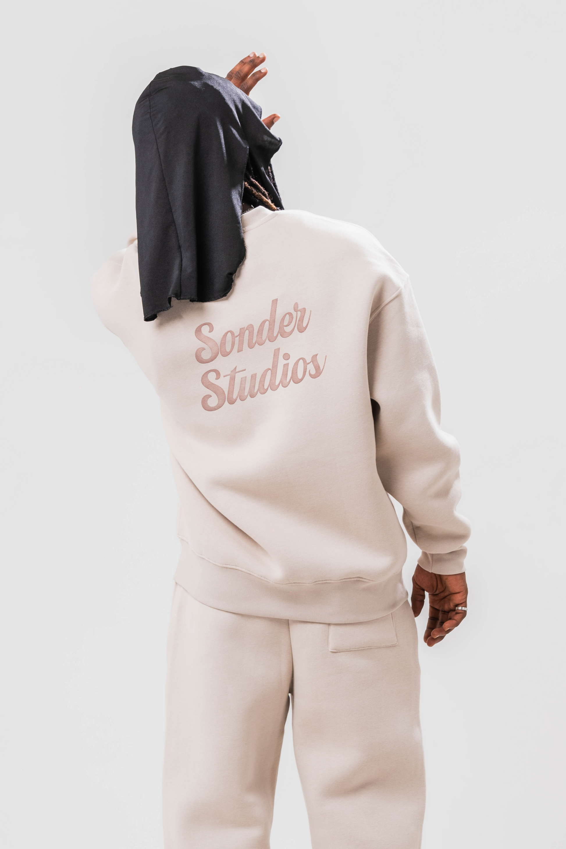 Back view of Male model wearing the Sonder Off-White Oversized sweatshirt with the oversized joggers. Standing in front of a light grey background.