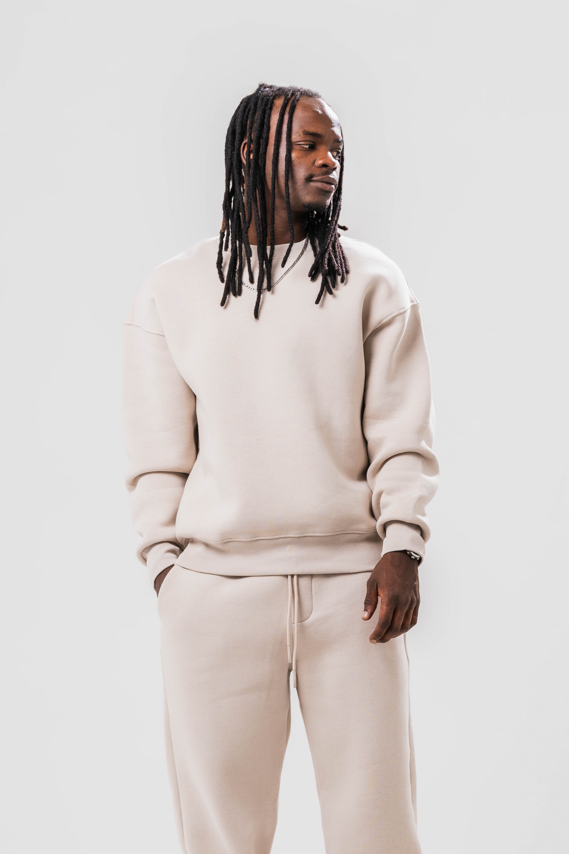 Male model wearing the Sonder Off-White Oversized sweatshirt with the oversized joggers. Standing in front of a light grey background.