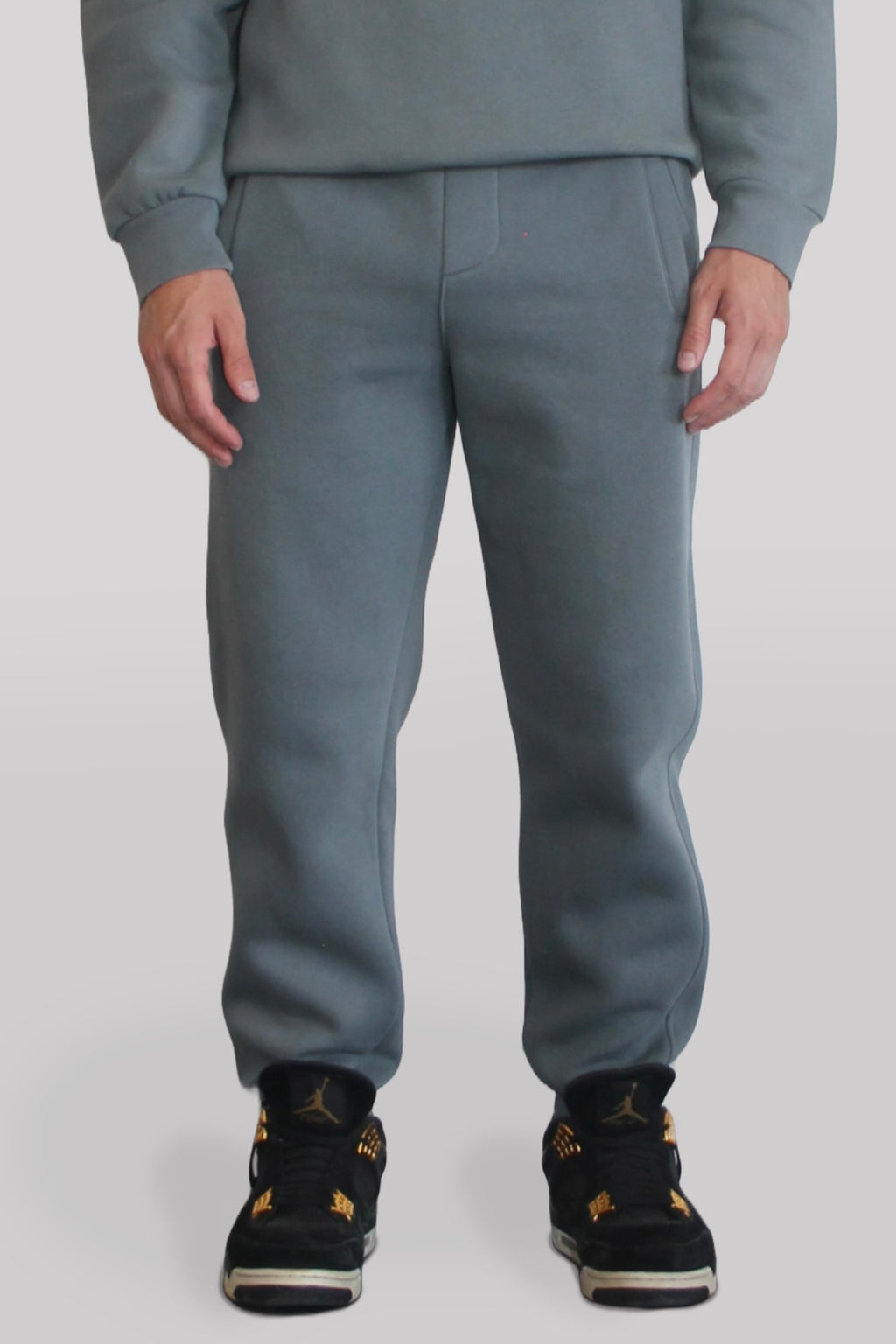 Male model wearing the Sonder Shadow Grey Signature Series Sweatpants paired with the Shadow Grey Signature Series Sweatshirt. In front of a light grey background.