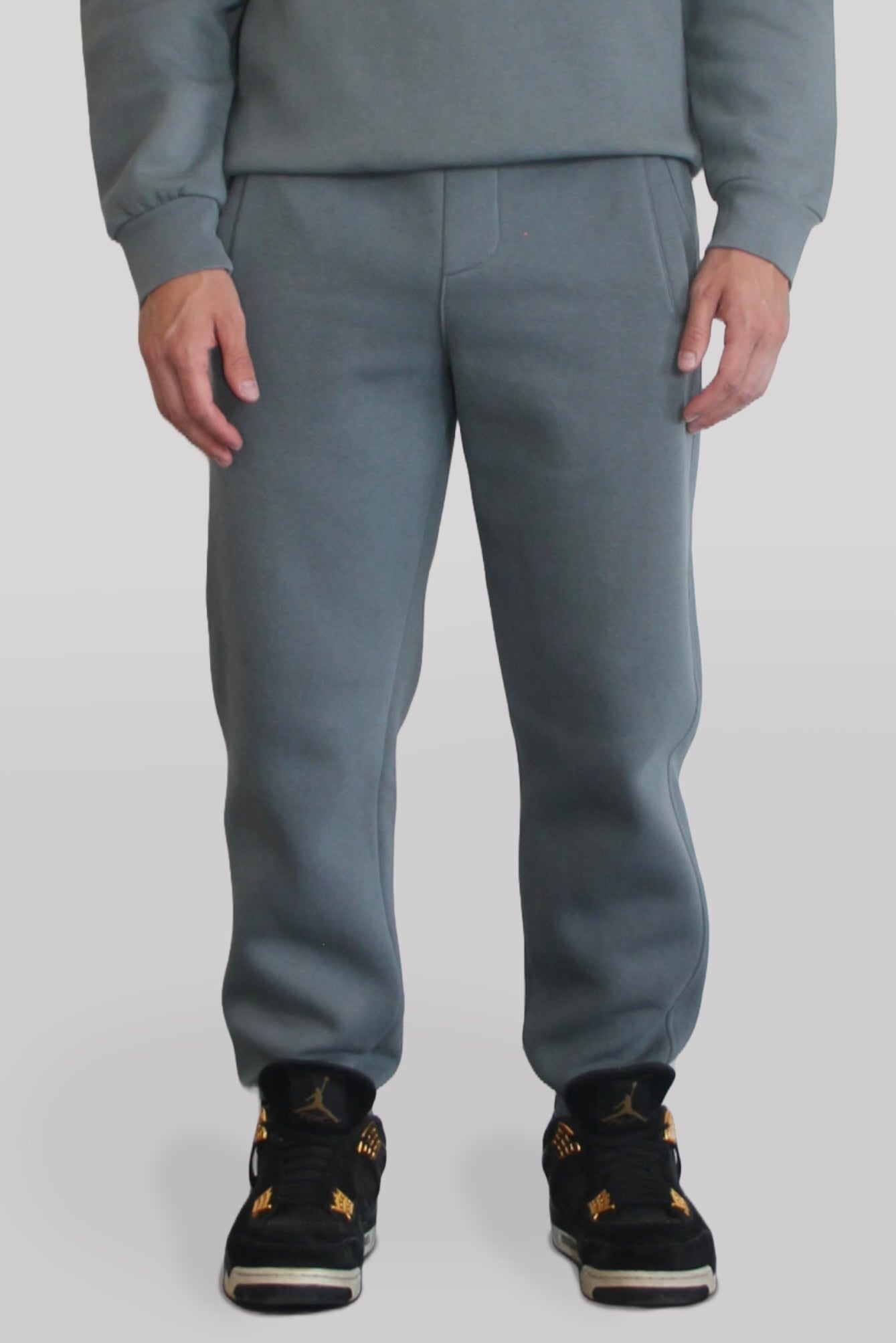 Male model wearing the Sonder Shadow Grey Signature Series Sweatpants paired with the Shadow Grey Signature Series Sweatshirt. In front of a light grey background.