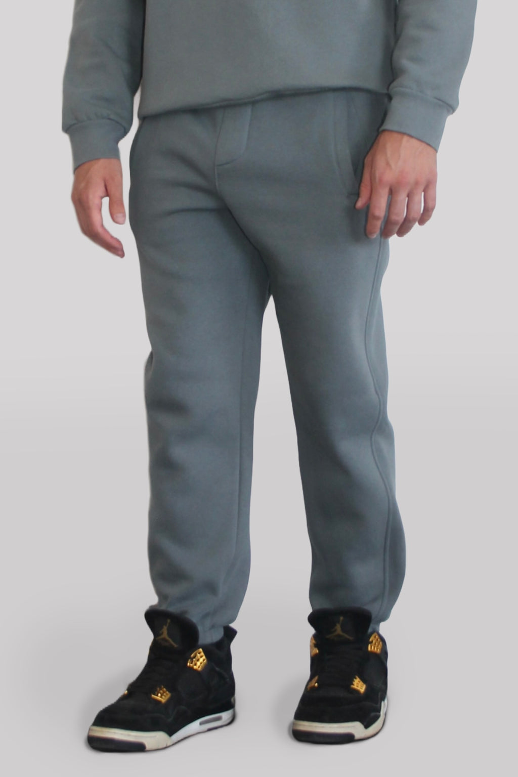 Side view of Male model wearing the Sonder Shadow Grey Signature Series Sweatpants paired with the Shadow Grey Signature Series Sweatshirt. In front of a light grey background.
