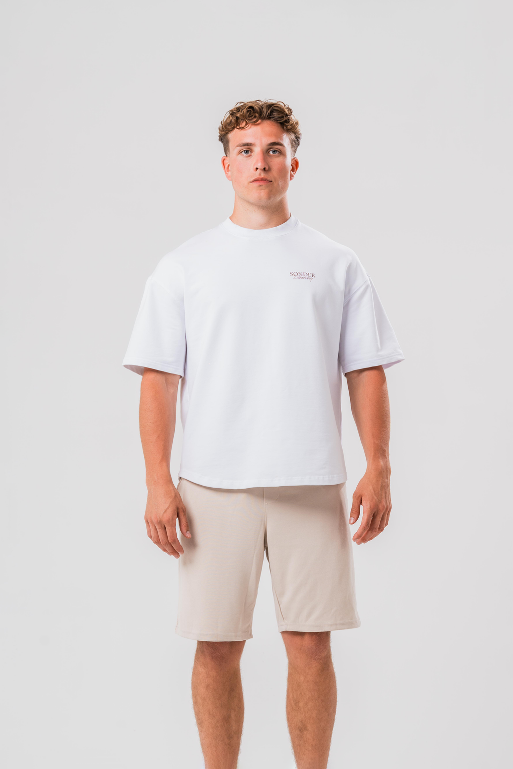 Male model wearing the Sonder White cowboy tee and beige shorts, in front of a light grey background