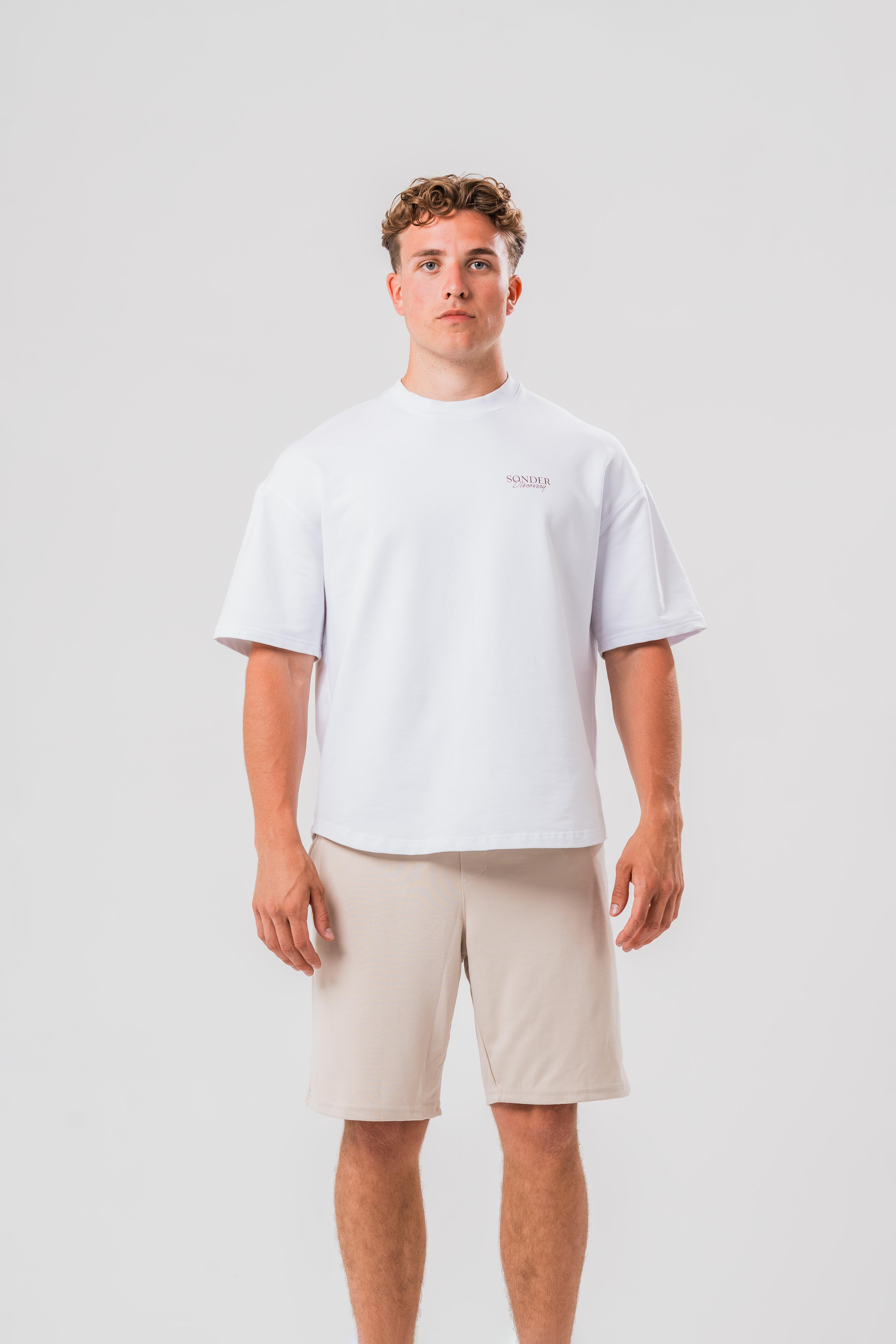 Male model wearing the Sonder White cowboy tee and beige shorts, in front of a light grey background