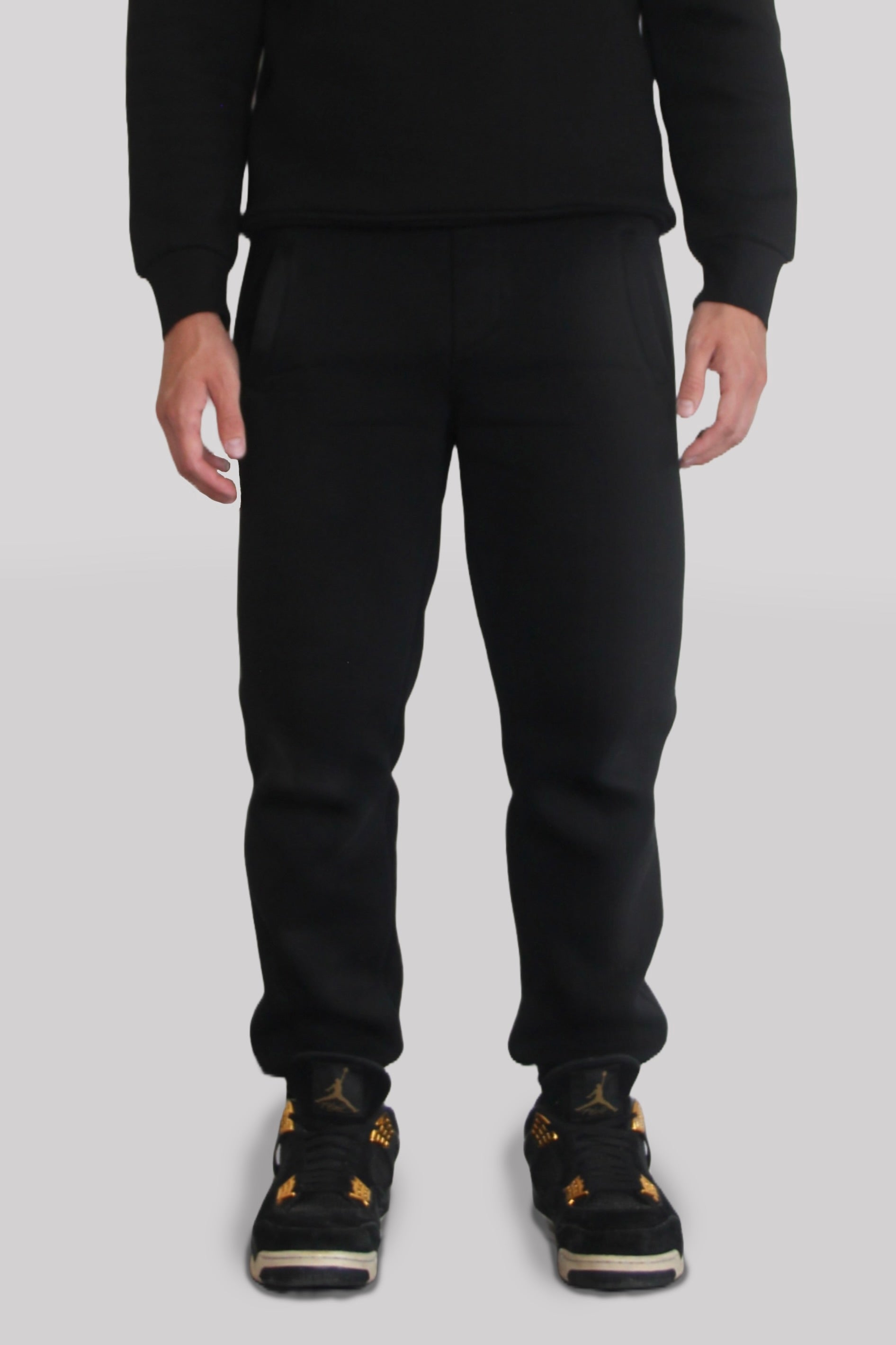 Male model wearing the Sonder black Signature Series Sweatpants paired with the Black Signature Series Sweatshirt. In front of a light grey background