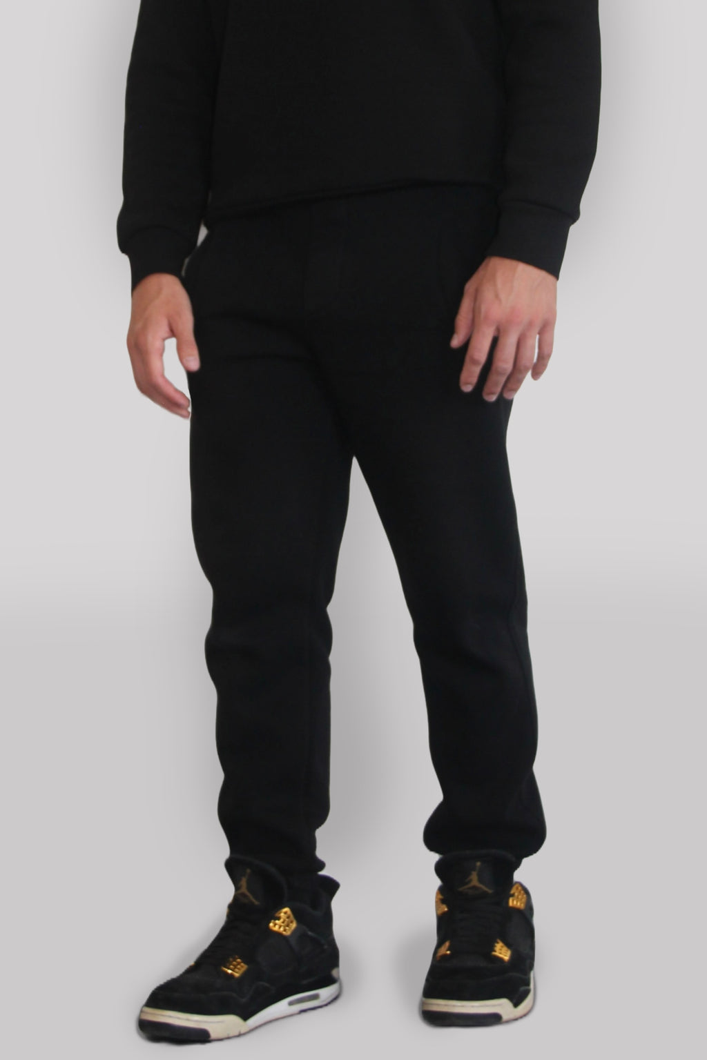 Side view of Male model wearing the Sonder black Signature Series Sweatpants paired with the Black Signature Series Sweatshirt. In front of a light grey background
